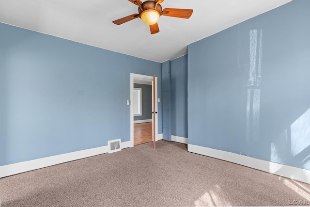 empty room with carpet flooring, visible vents, baseboards, and a ceiling fan
