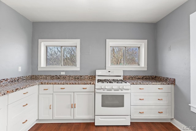kitchen with white cabinetry, white gas range, dark stone counters, and dark wood finished floors