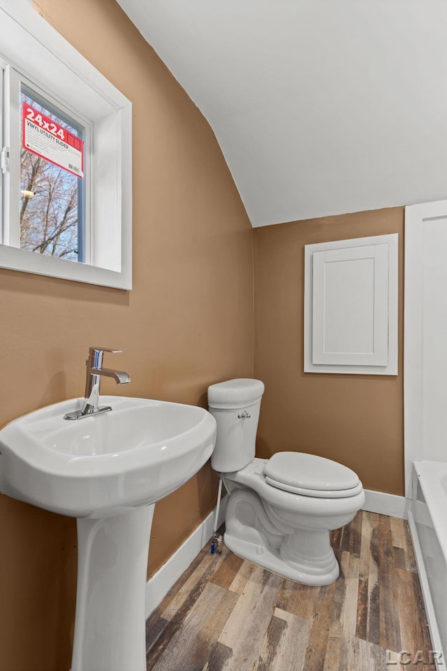 full bathroom with toilet, wood finished floors, baseboards, and lofted ceiling