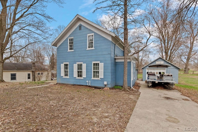 view of home's exterior with concrete driveway, a detached carport, and an outbuilding