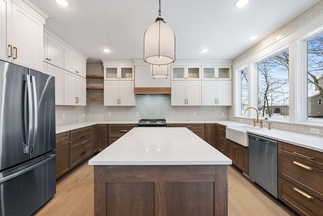 kitchen featuring stainless steel appliances, open shelves, white cabinets, a sink, and light wood finished floors