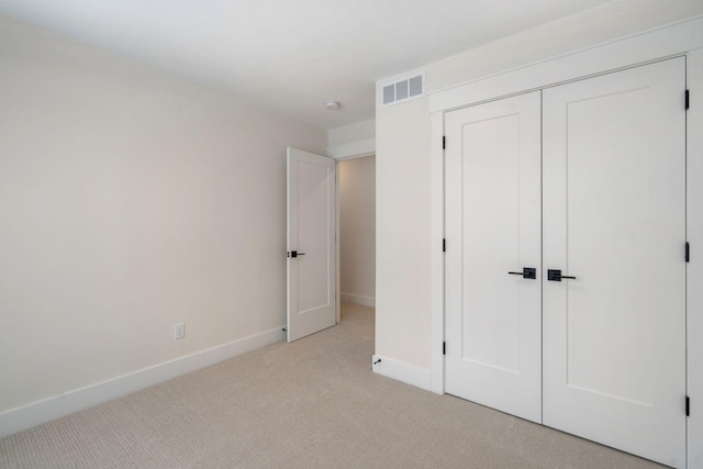 unfurnished bedroom with light colored carpet, baseboards, and a closet