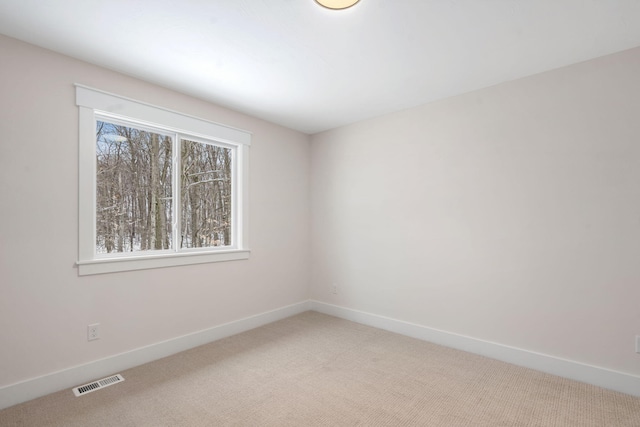 unfurnished room featuring light carpet and baseboards