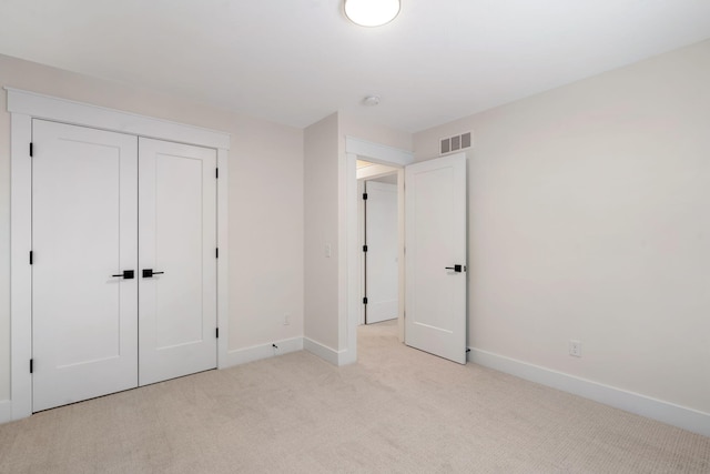 unfurnished bedroom with light colored carpet, baseboards, and a closet