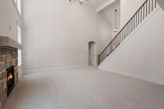 unfurnished living room with high vaulted ceiling, a fireplace, arched walkways, beam ceiling, and a decorative wall