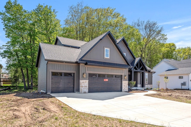 view of front of property with concrete driveway, an attached garage, a shingled roof, board and batten siding, and stone siding