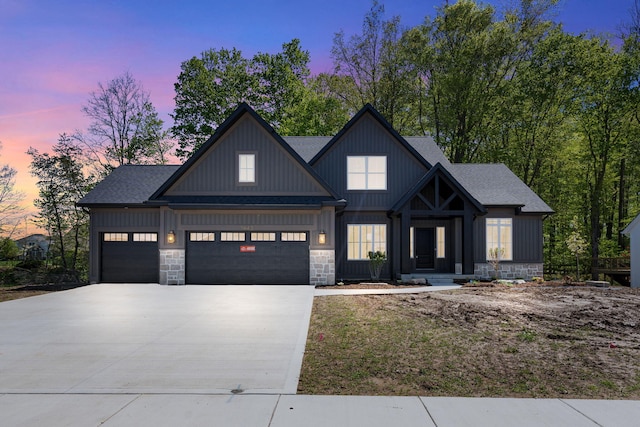 modern inspired farmhouse with driveway, a garage, stone siding, and roof with shingles