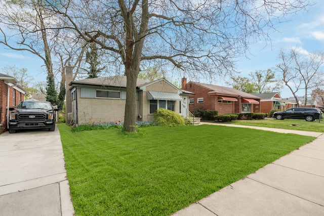 view of front facade with a chimney, concrete driveway, a front lawn, and brick siding