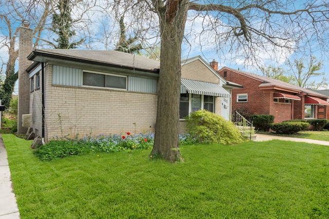 view of front of home with a chimney, a front lawn, and brick siding