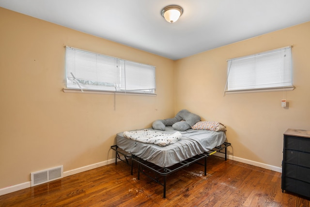 bedroom featuring visible vents, baseboards, and wood finished floors
