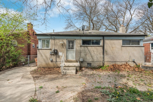 back of house with fence, a chimney, and brick siding