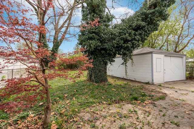 view of yard with a garage, fence, an outbuilding, and concrete driveway