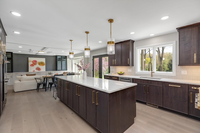 kitchen featuring a sink, light wood-style flooring, open floor plan, decorative backsplash, and recessed lighting