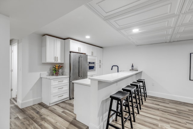245 Chestnut Cir, Bloomfield Hills, MI 48304 - kitchen featuring stainless steel appliances, a breakfast bar, baseboards, recessed lighting, and light wood-style flooring