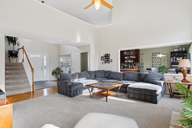 1826 Poppleton Dr, West Bloomfield, MI 48324 - living room with a towering ceiling, a ceiling fan, carpet floors, stairs, and wood finished floors