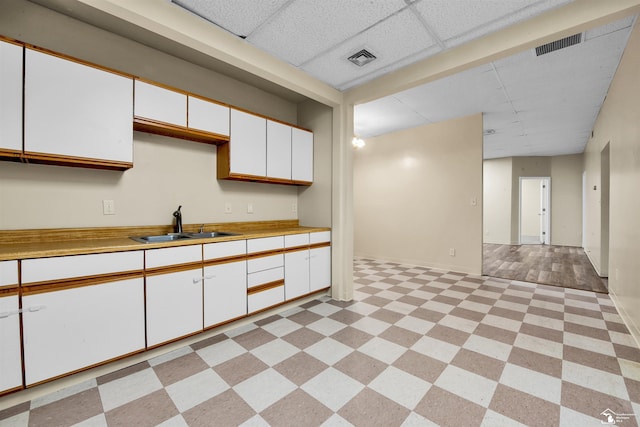 12800 Matthews St, Carleton, MI 48117 - kitchen with a sink, white cabinets, light countertops, a drop ceiling, and baseboards