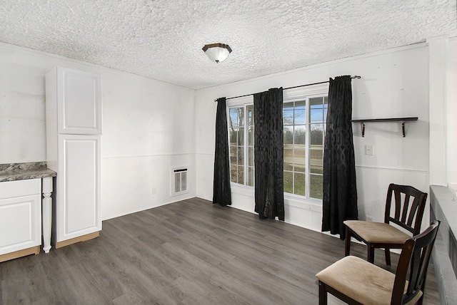 interior space with a textured ceiling, heating unit, and dark wood-style floors