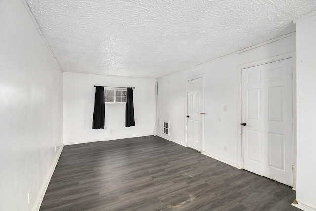 unfurnished room with a textured ceiling, baseboards, and dark wood finished floors