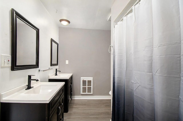 full bath with visible vents, baseboards, a sink, and wood finished floors
