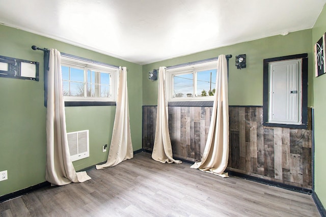 empty room featuring a wealth of natural light, wainscoting, and wood finished floors