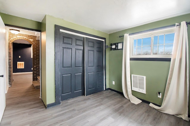 interior space with light wood-style floors, arched walkways, visible vents, and baseboards