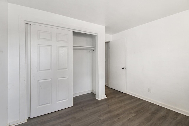unfurnished bedroom featuring a closet, baseboards, and dark wood finished floors