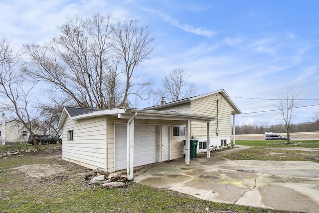 exterior space with a chimney, a garage, and concrete driveway