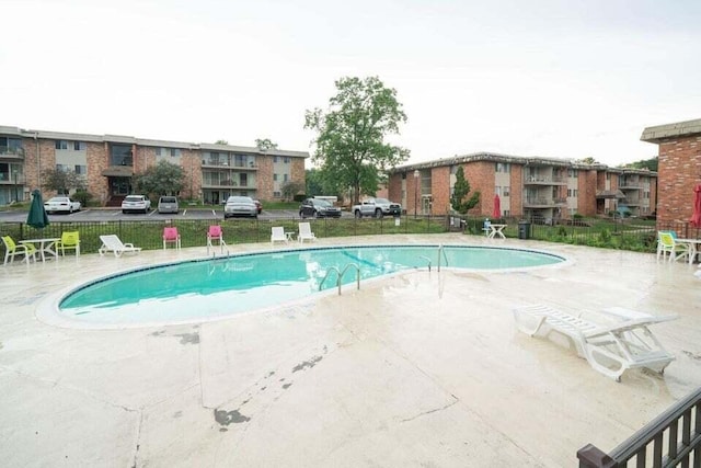 community pool with a patio area and fence