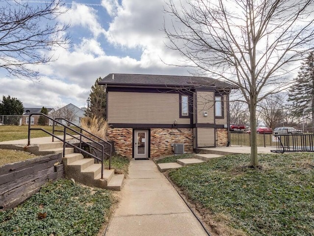 view of front of property with brick siding, fence, and central AC unit