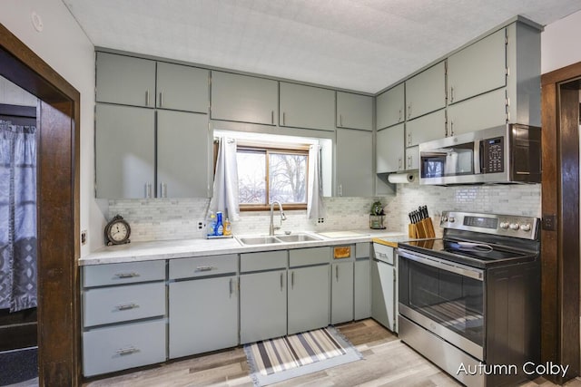 kitchen with a sink, gray cabinetry, and stainless steel appliances