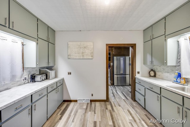 kitchen with light wood-style floors, tasteful backsplash, and freestanding refrigerator