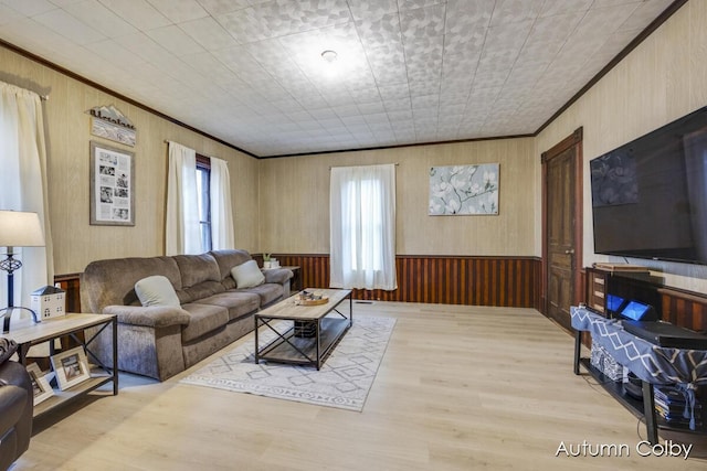 living area with wooden walls, ornamental molding, and light wood finished floors