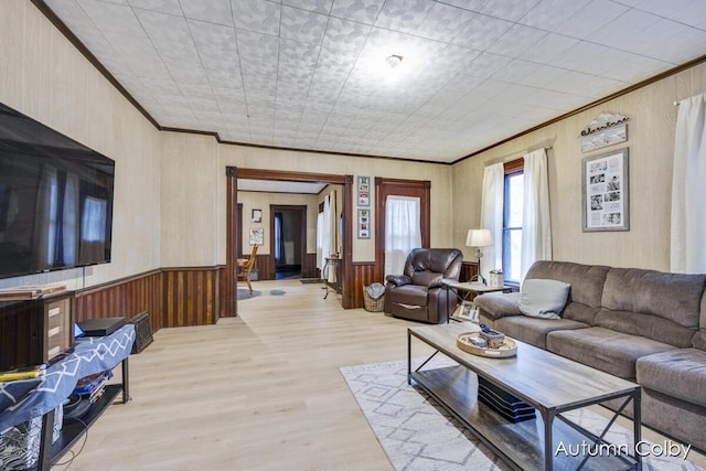 living room featuring crown molding, light wood-type flooring, and wood walls