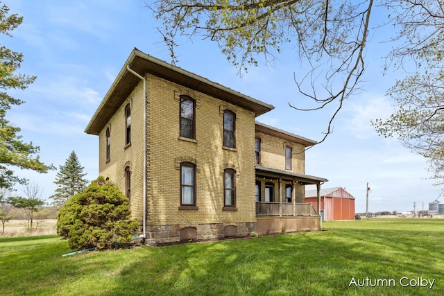 back of house featuring brick siding and a yard