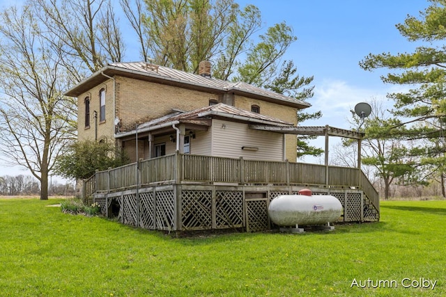 rear view of house featuring a standing seam roof, a chimney, metal roof, a deck, and a yard