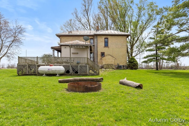rear view of house featuring a chimney, a yard, a deck, and metal roof