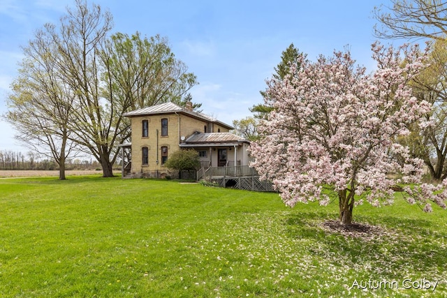 exterior space with a lawn, a standing seam roof, metal roof, and a chimney