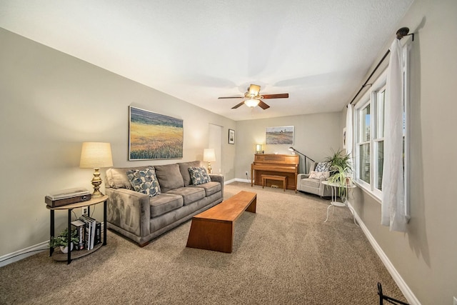 carpeted living area with ceiling fan and baseboards
