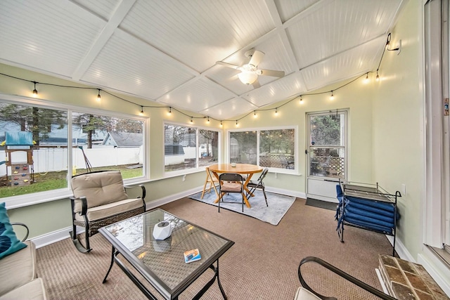 sunroom featuring ceiling fan, outdoor dining area, lofted ceiling with beams, and baseboards