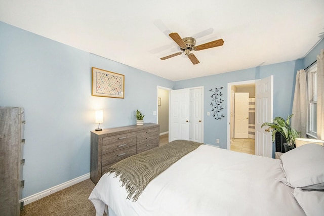 bedroom featuring baseboards, connected bathroom, ceiling fan, and light carpet