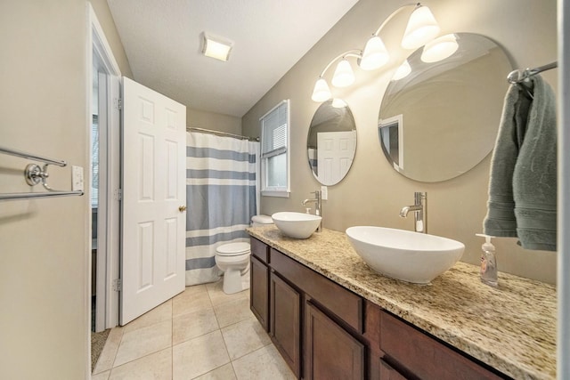 bathroom with tile patterned flooring, double vanity, a sink, and toilet