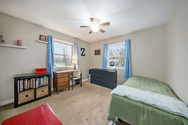 carpeted bedroom featuring multiple windows, baseboards, and ceiling fan