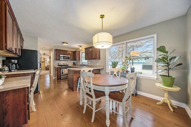 dining room with plenty of natural light, wood-type flooring, baseboards, and a textured ceiling