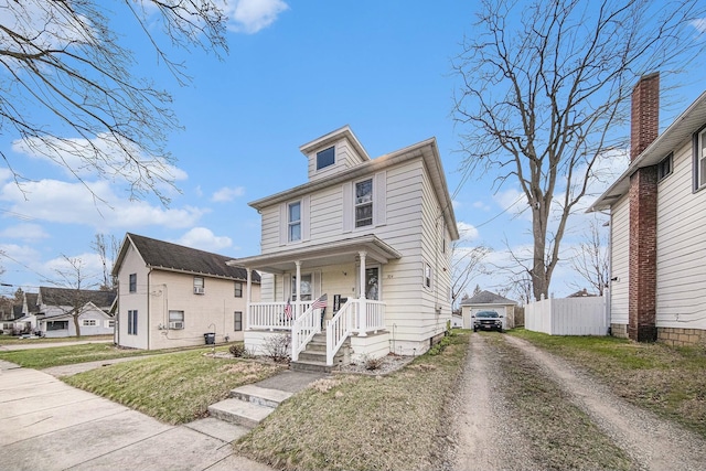 traditional style home with a front yard, fence, covered porch, and driveway