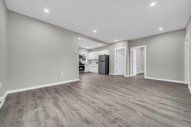 unfurnished living room with recessed lighting, light wood-style floors, and baseboards