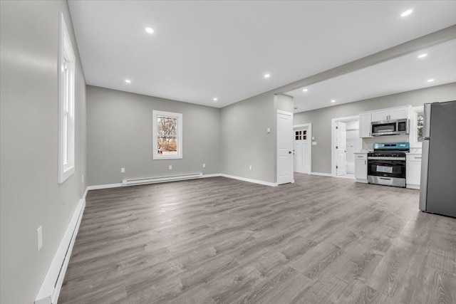 unfurnished living room with baseboard heating, a baseboard radiator, wood finished floors, and recessed lighting