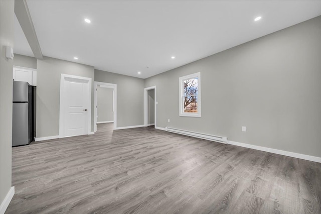 unfurnished living room featuring recessed lighting, light wood-style flooring, a baseboard radiator, and baseboards