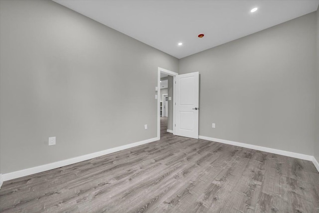 spare room with baseboards, recessed lighting, and wood finished floors