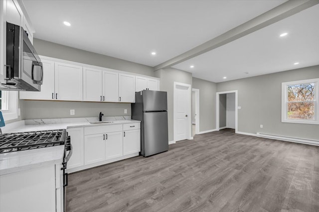 kitchen featuring light wood-type flooring, light stone counters, a baseboard heating unit, a sink, and stainless steel appliances