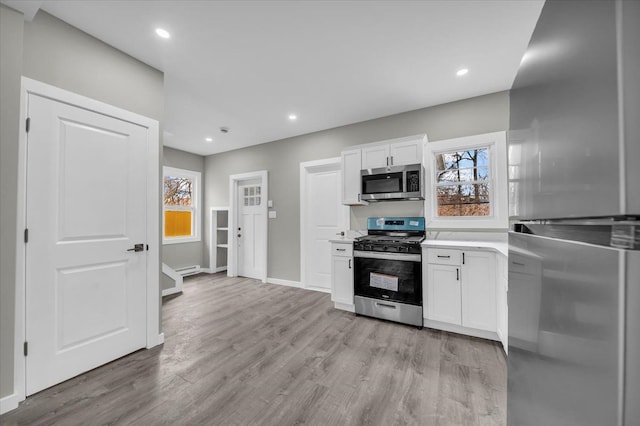 kitchen featuring light wood-type flooring, appliances with stainless steel finishes, light countertops, and white cabinetry
